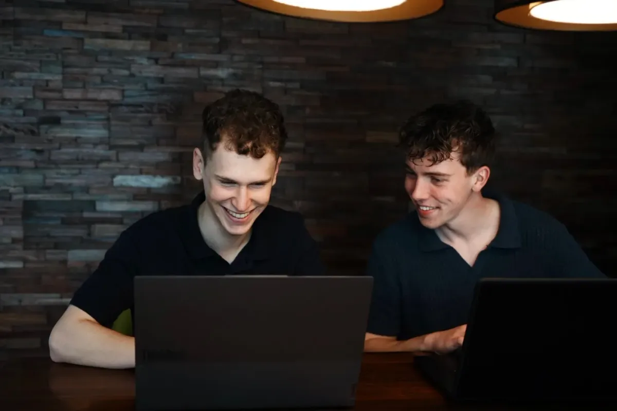 Jesse Lamm en Tim Lind werken samen achter hun laptops en lachen